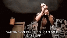 a man is singing into a microphone in a dark room while waiting on relief so he can go on days off .