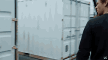 a man in a black shirt is standing in front of a white container with uc written on the bottom