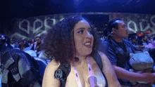 a woman with curly hair is smiling in front of a sign that says ' a '