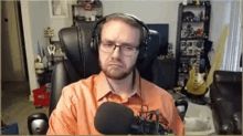 a man wearing headphones and glasses is sitting in front of a microphone