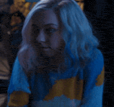 a woman with blue hair is wearing a blue and yellow striped sweater .