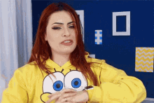 a woman with red hair wearing a yellow spongebob hoodie