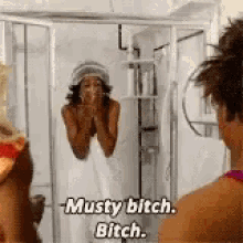 a woman wrapped in a towel is standing in front of a mirror in a shower .