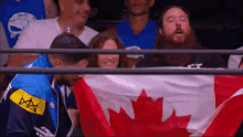 a man holding a canadian flag behind a fence