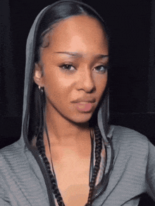a woman wearing a grey hoodie with a braided headband looks at the camera