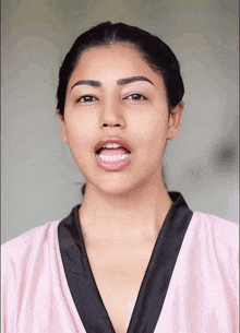 a woman wearing a pink robe is making a funny face