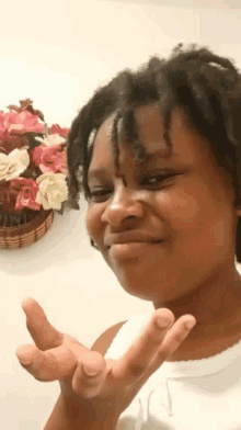 a person making a peace sign with a basket of flowers behind them