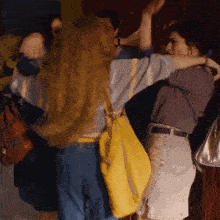 a woman with a yellow purse is hugging another woman