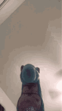 a stuffed animal with a fishnet socks on it is standing in front of a ceiling fan .
