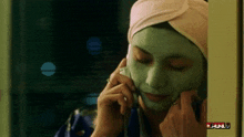a woman with a green mask on her face is talking on a phone