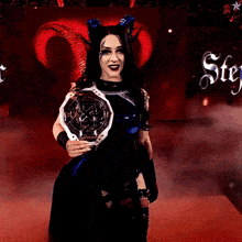 a woman with horns is holding a trophy in front of a sign that says stey