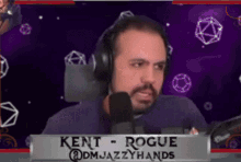 a man wearing headphones is sitting in front of a microphone and a sign that says kent rogue