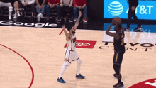 a basketball game is being played in front of an ad for google and at & t