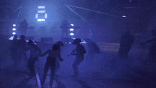 a group of people are dancing in a dark room with a sign that says ' ii ' on it