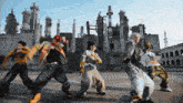 a group of people are dancing in front of a building