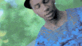 a man with tattoos on his chest is wearing a blue shirt and hat