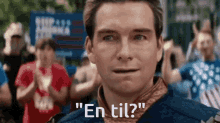 a man standing in front of a crowd with the words " en til " written on his face