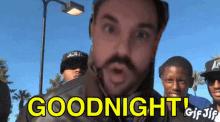 a man with a beard and mustache is standing in front of a group of men and says goodnight .
