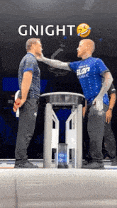 two men are standing next to each other and one of them is wearing a blue shirt with the word slap on it .