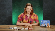 a woman sits at a table with cards and a box of second chances