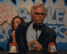 a man in a suit and bow tie stands in front of a sign that says baby billy