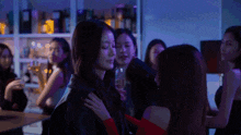 a group of women are gathered in a dark room and one woman is hugging another woman