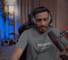 a man wearing headphones is covering his face while sitting in front of a red light .