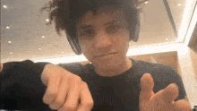 a young man wearing headphones is pointing at the camera and making a funny face .