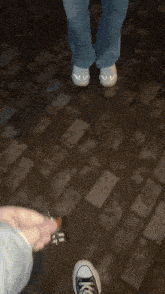 a person holding a pair of scissors on a brick sidewalk