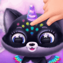 a cat with a unicorn horn and wings is being touched by a person 's finger .