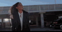 a woman in a suit stands in a parking lot
