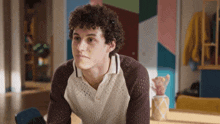 a young man with curly hair is sitting at a table in a living room .