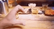 a person is typing on a cell phone while sitting at a table with drinks and food .