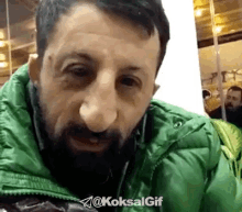 a man with a beard is wearing a green jacket with the hashtag @koksalgif on it