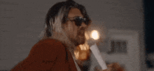 a man with long blonde hair is singing into a microphone .