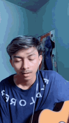 a man wearing a blue shirt with the word obey on it is playing a guitar