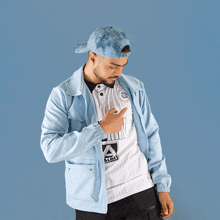 a man wearing a light blue jacket and a white shirt with an a logo on it