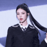 a woman in a black suit and tie is holding her hair in a ponytail