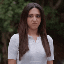 a woman wearing a white shirt has a serious look on her face .