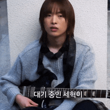 a man playing a guitar with korean writing on the bottom