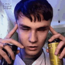 a young man is holding a can of energy drink in his hands and covering his ears .