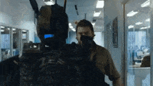 a man is standing next to a robot in a hallway holding a gun .