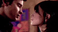 a man and a woman are kissing in front of a painting
