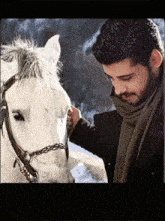 a man petting a white horse with a bridle