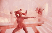 a woman in a pink dress is dancing in front of flowers