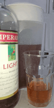 a bottle of light brandy next to a cup