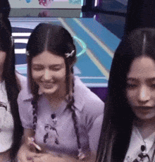 a woman in a purple shirt is smiling while standing next to two other girls