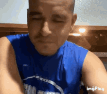 a man wearing a blue tank top with the word orlando on it looks at the camera with his eyes closed