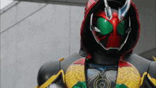 a masked superhero with a black and red helmet and green eyes