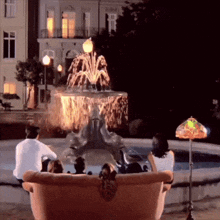 a group of people sitting in front of a fountain